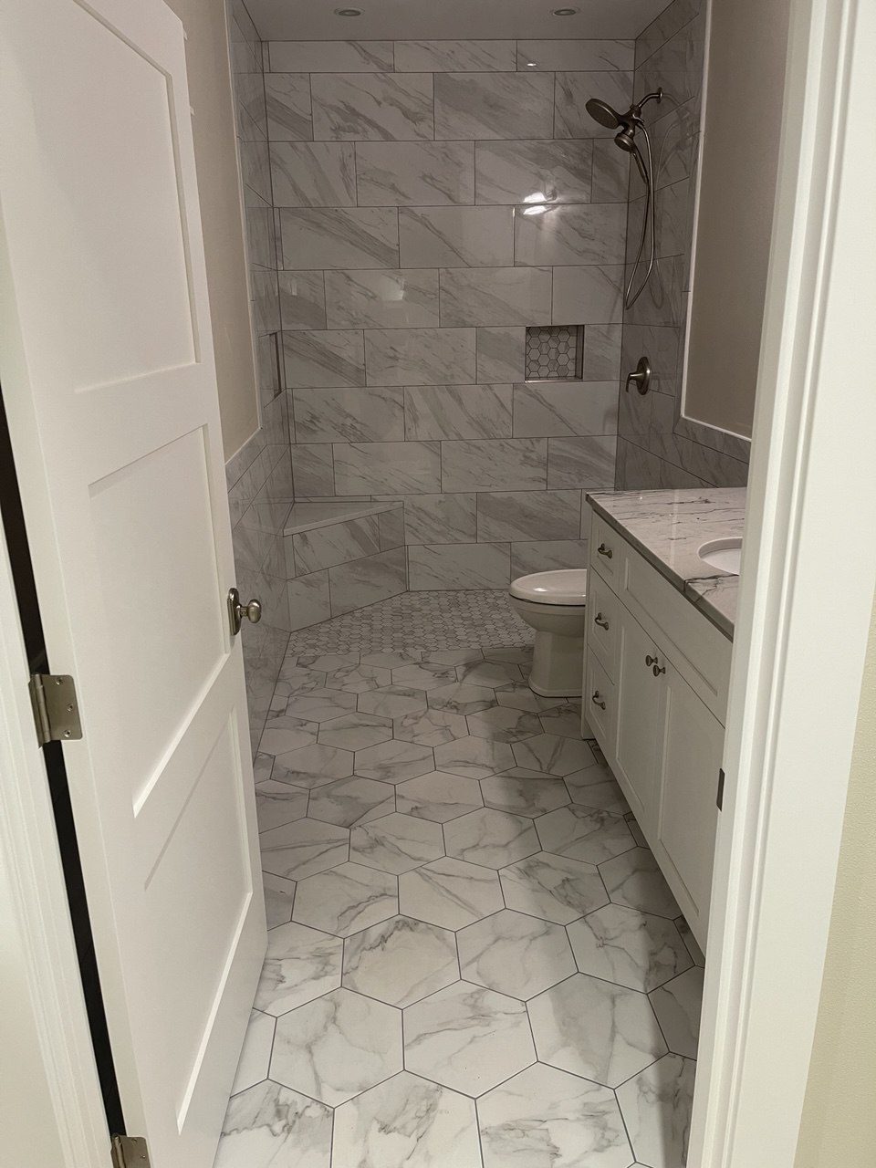 Finished bathroom tiled in marble-look porcelain with a shaker vanity