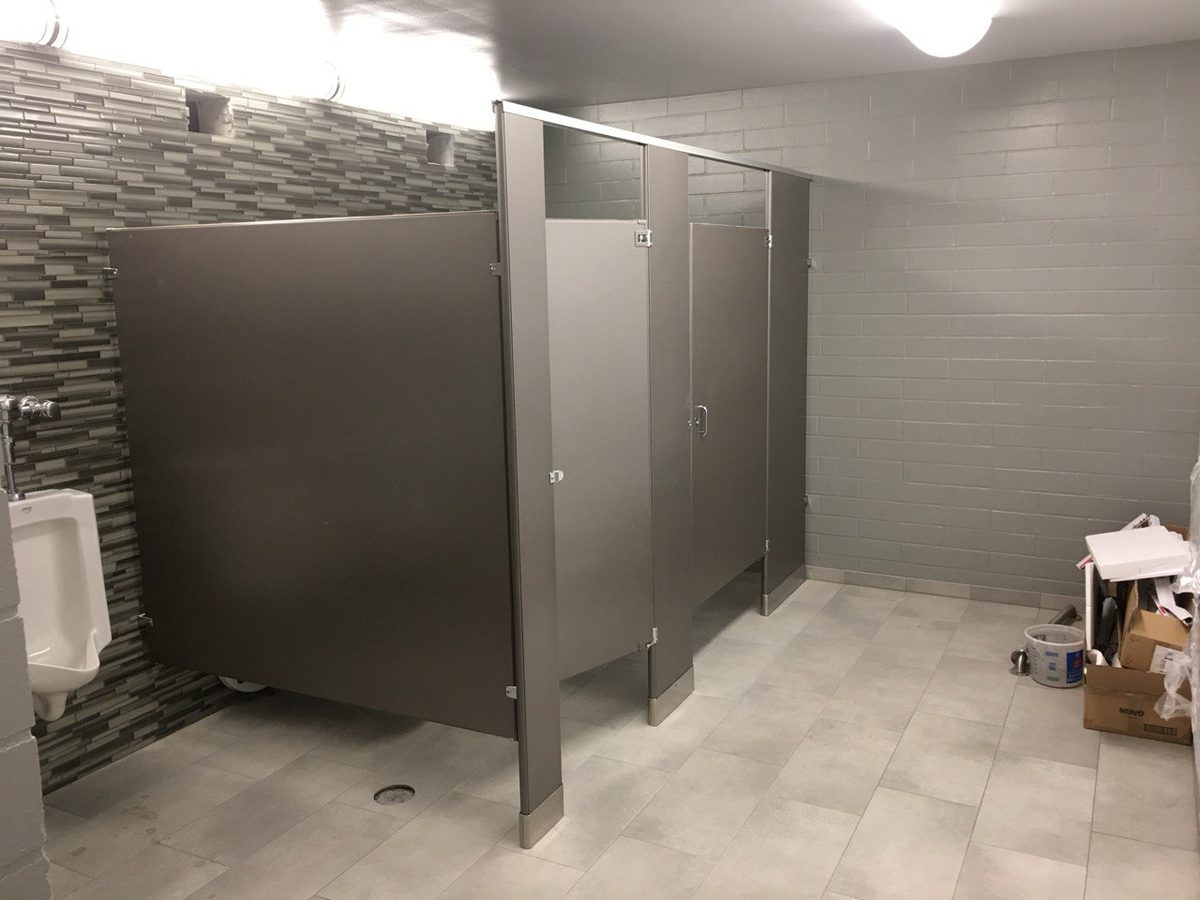 A finished commercial restroom with floor-mounted partitions and tiled walls