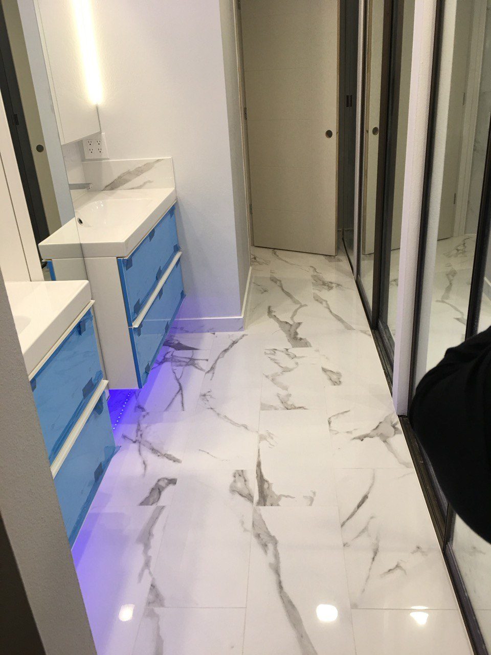 A floating vanity and large-format marble-look floor tile during a bathroom build