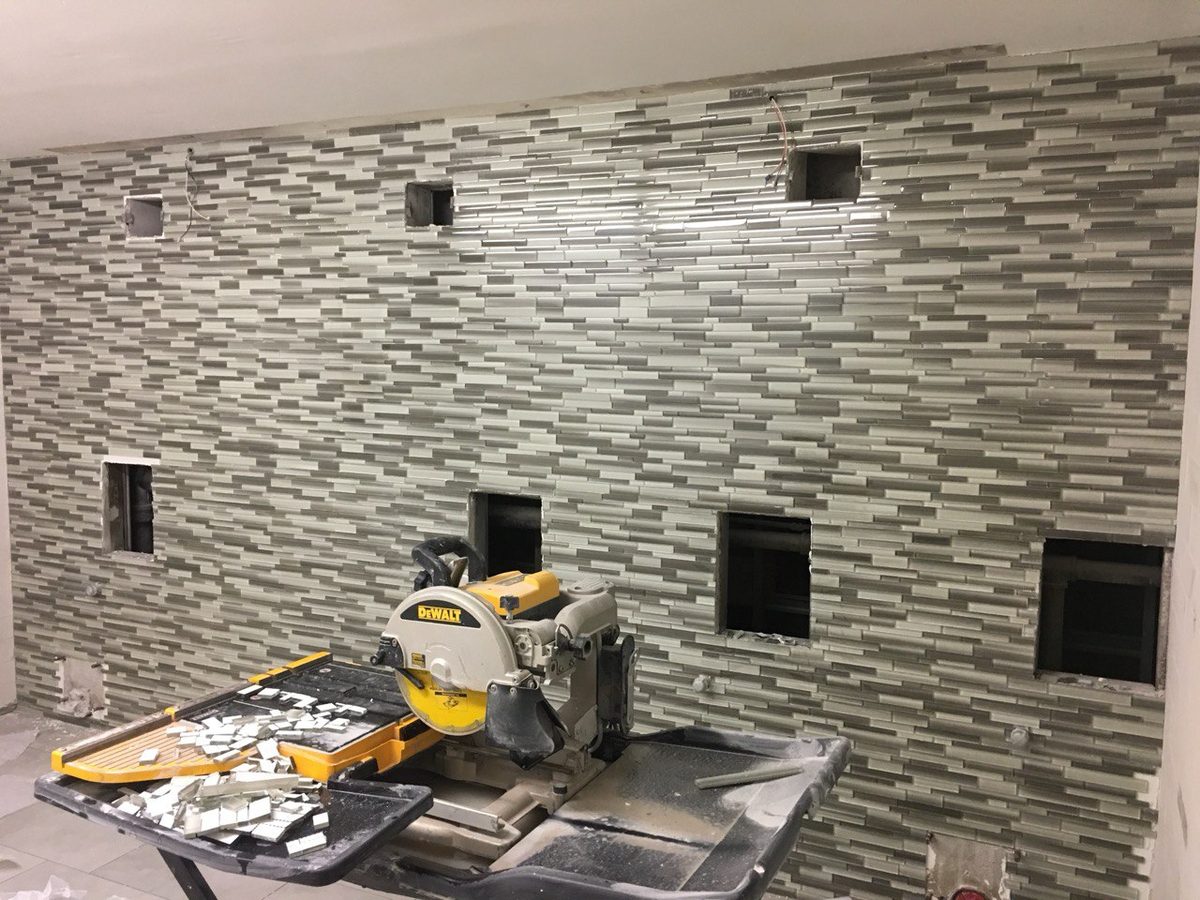 A stacked mosaic tile backsplash being installed, with the tile saw and materials set up on site