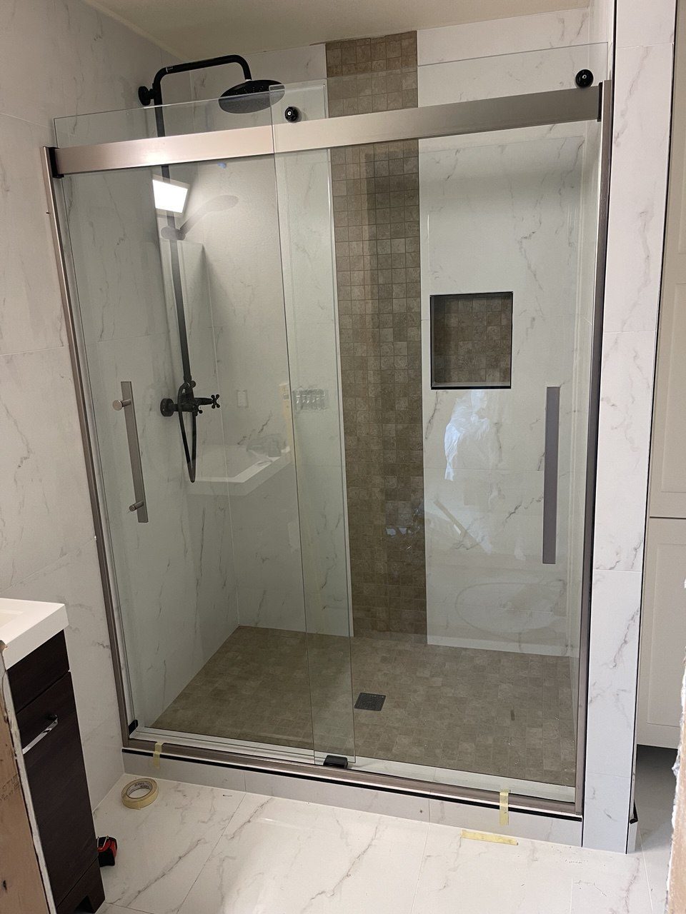 Finished shower with a matte black rainfall head and marble-look tiled walls