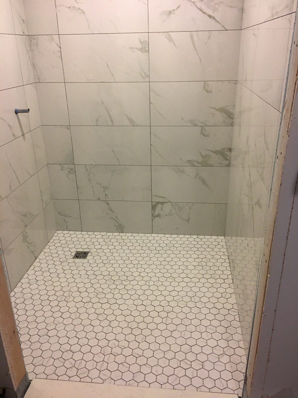Finished shower with large-format wall tile and a hexagon tile floor
