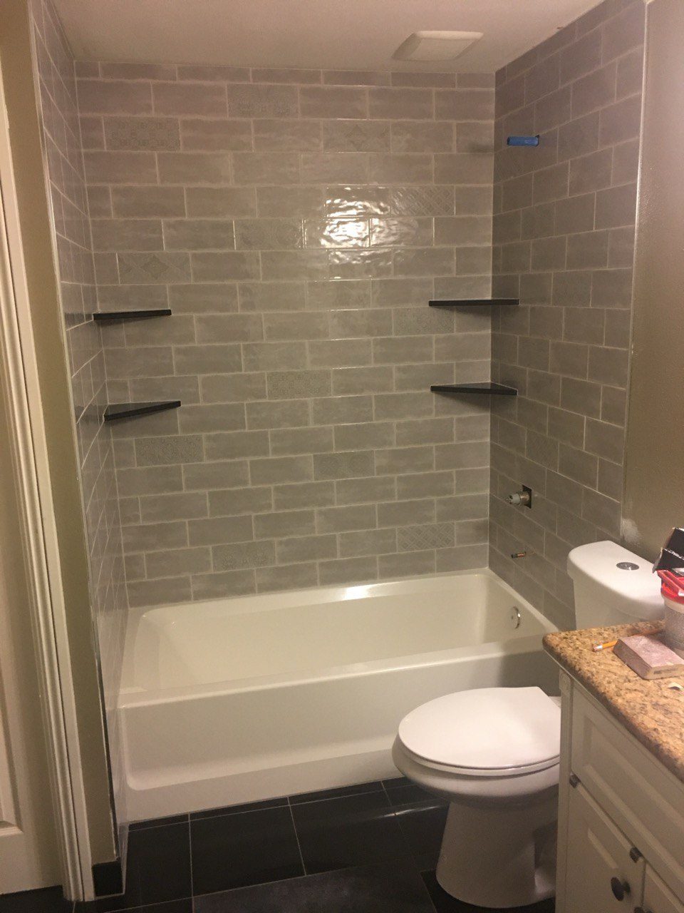 Finished tub-shower tiled in subway tile with built-in corner shelves
