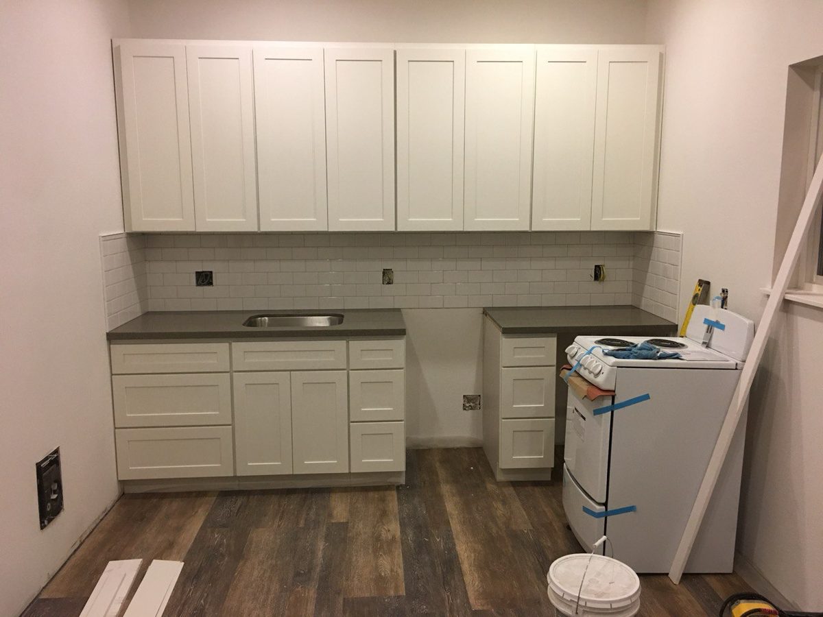 Finished utility room with white cabinetry, a countertop run and plank flooring
