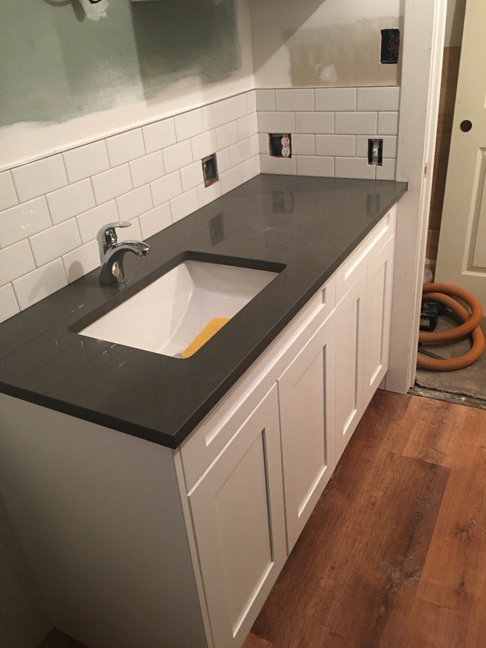 Bathroom vanity with a white shaker cabinet, charcoal quartz countertop, undermount sink and white subway tile backsplash