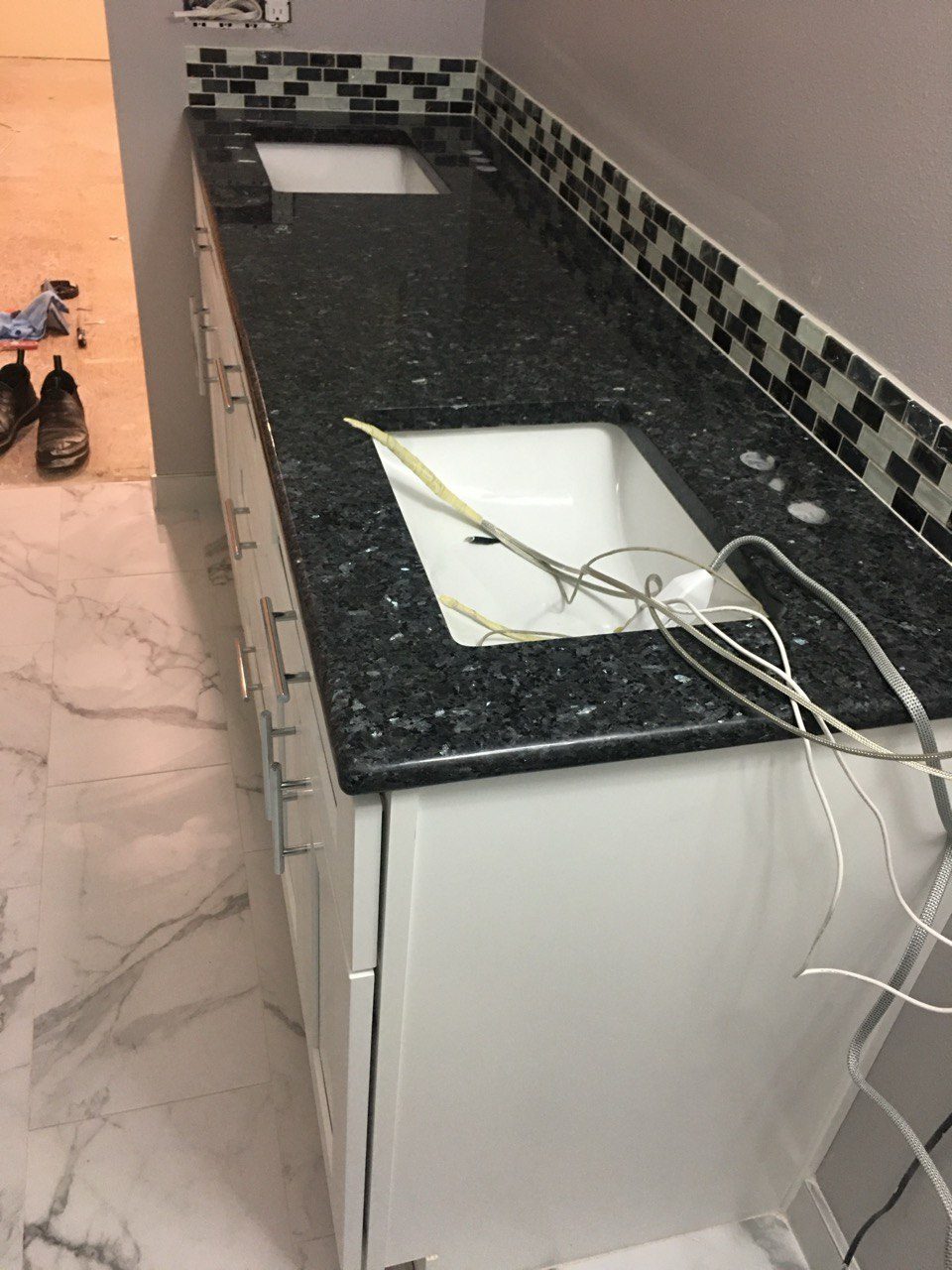 A vanity with a granite top and mosaic backsplash during installation